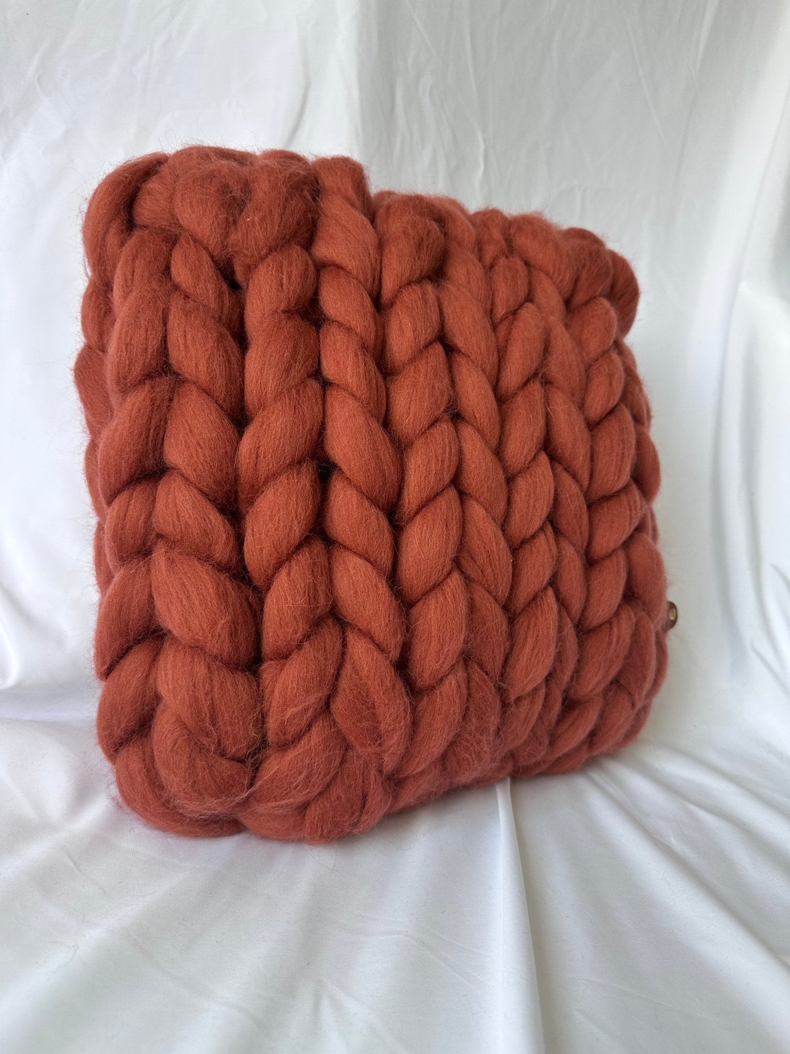 Créez une ambiance chaleureuse, dans votre espace grâce à ce coussin en laine mérinos à grosse maille, affichant une superbe teinte terracotta