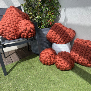 Apportez chaleur et raffinement à votre espace avec ce coussin en laine mérinos à grosse maille de 40x40 cm, dans une superbe nuance terracotta